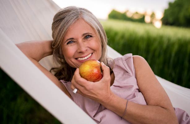 older woman eating apple outside