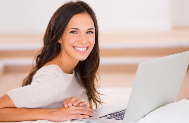 brunette woman sitting at laptop smiling