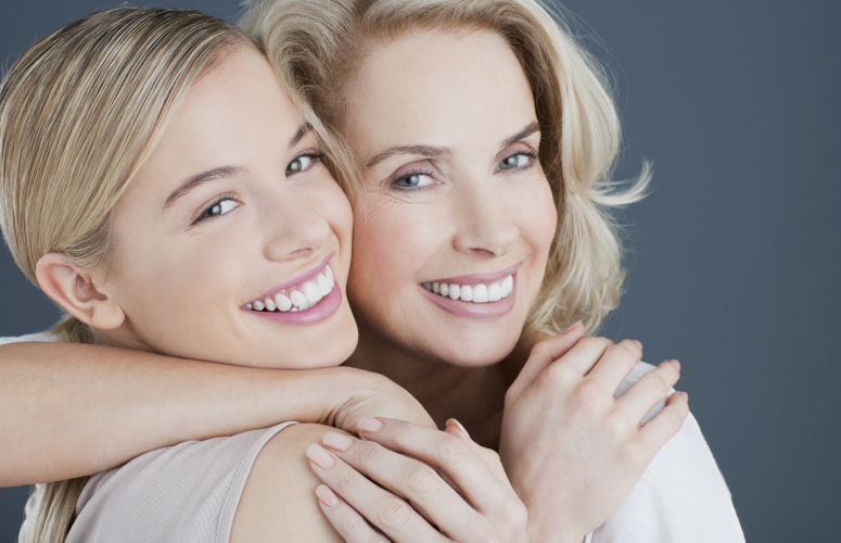 two blond women hug and smile to show off their straight teeth from Six Month Smiles braces