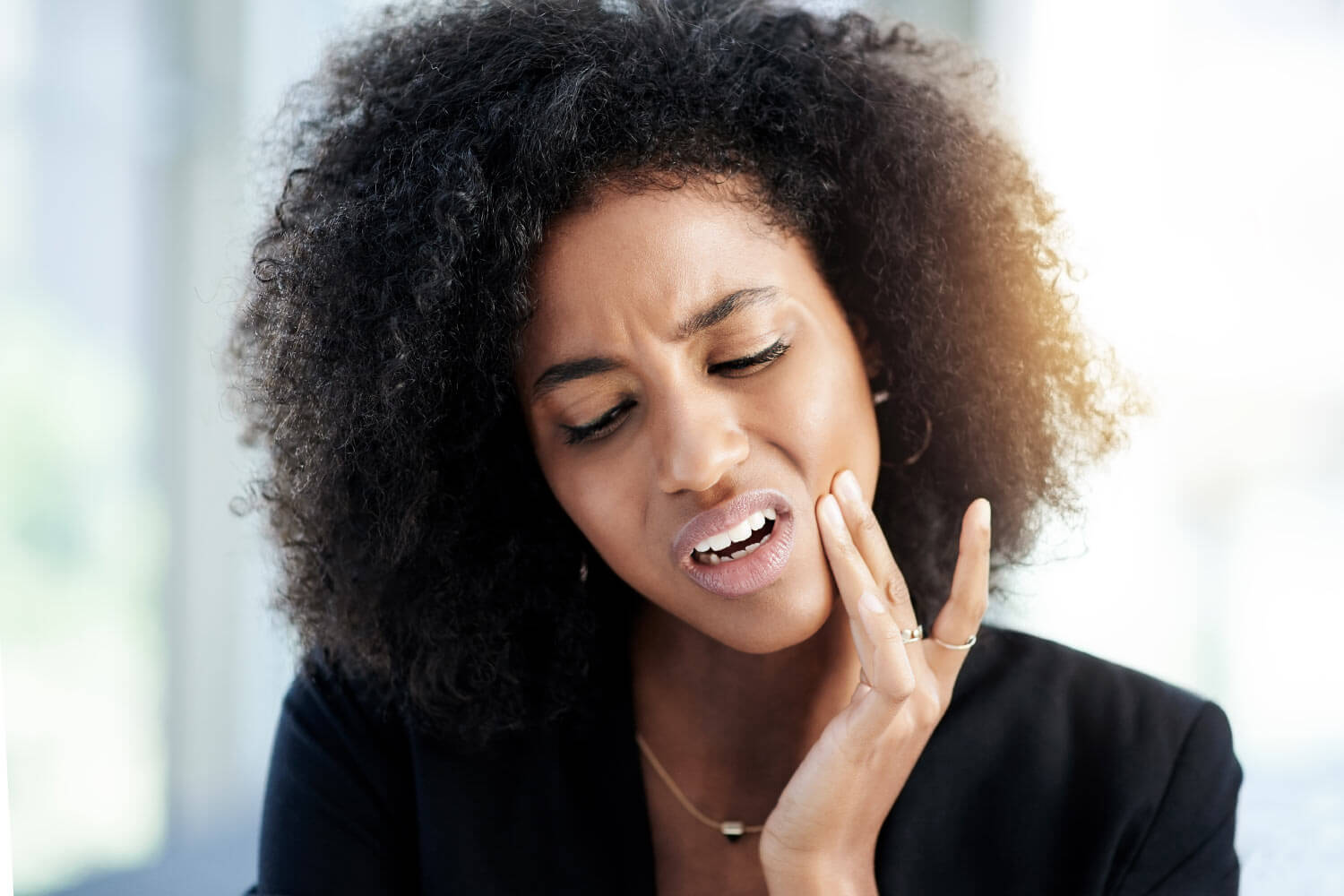 woman holds her jaw in pain with a dental emergency