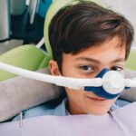 Young boy in the dental chair with a mask dispensing nitrous oxide dental sedation.