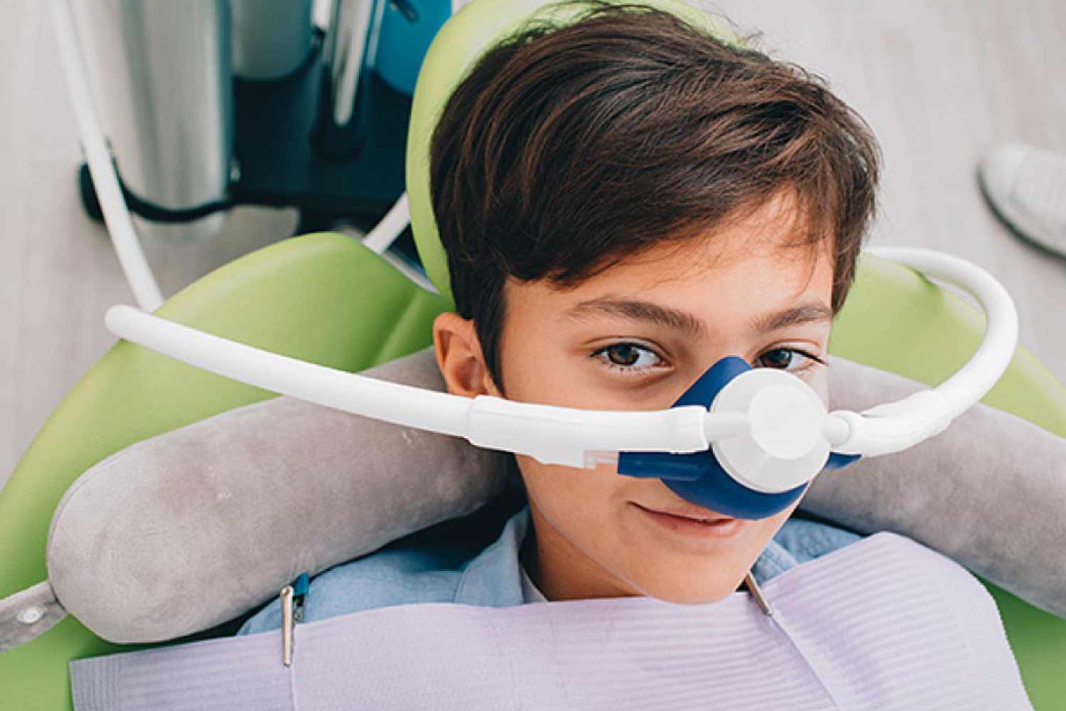 Young boy in the dental chair with a mask dispensing nitrous oxide dental sedation.