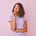 Young Brazilian woman in a lavender shirt thinks about her periodontal health with her hand under her chin