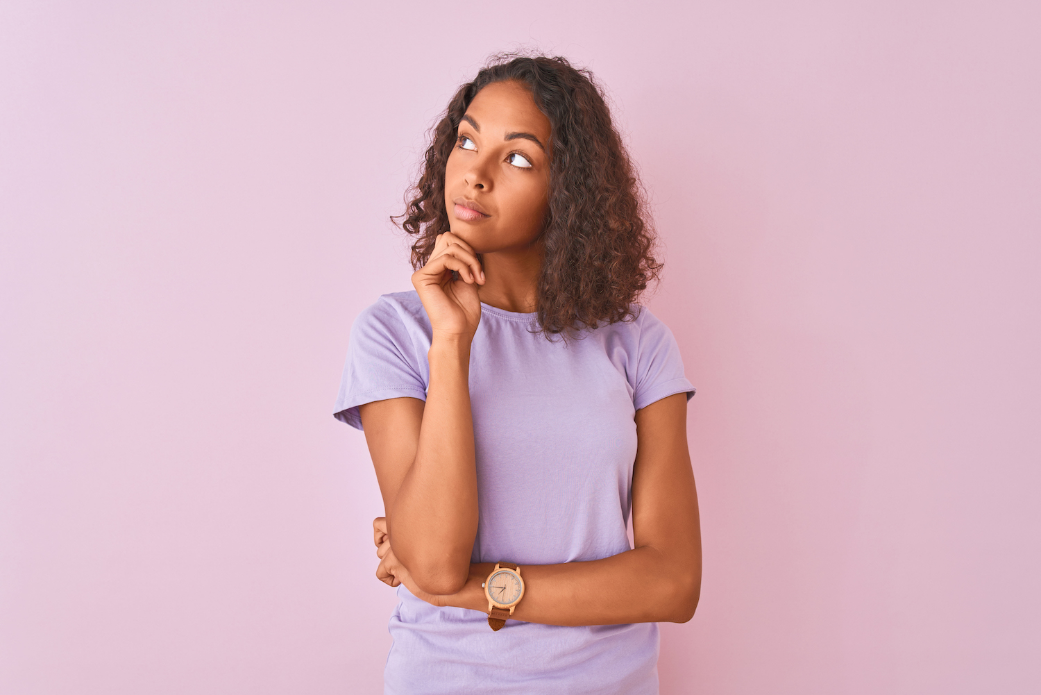 Young Brazilian woman in a lavender shirt thinks about her periodontal health with her hand under her chin