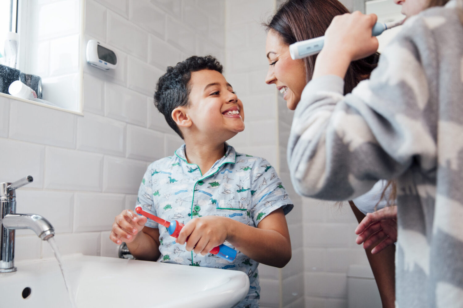 Young boy smiles at his mom after brushing his teeth at their bathroom sink