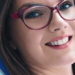 young woman wearing glasses sits in the dentist chair after geeting onlays on her teeth.