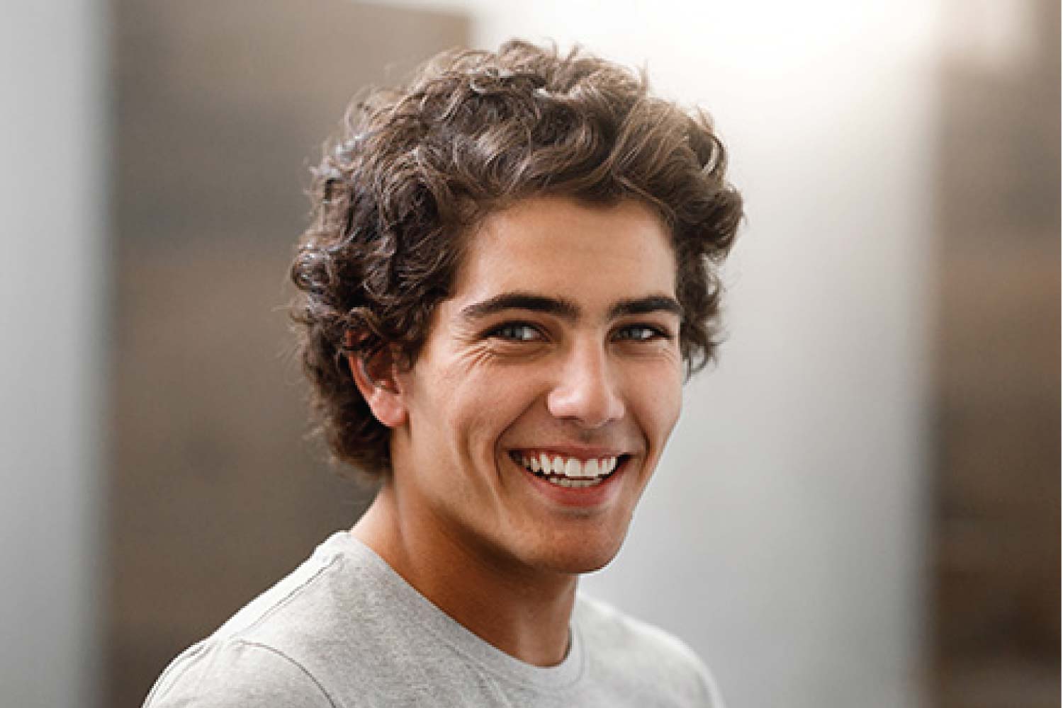 young man smiles showing off how tooth bonding repairs damaged teeth