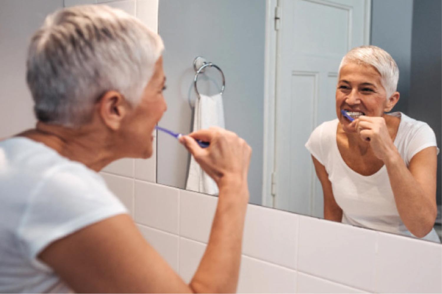 senior woman brushes her teeth to protect her dental restorations