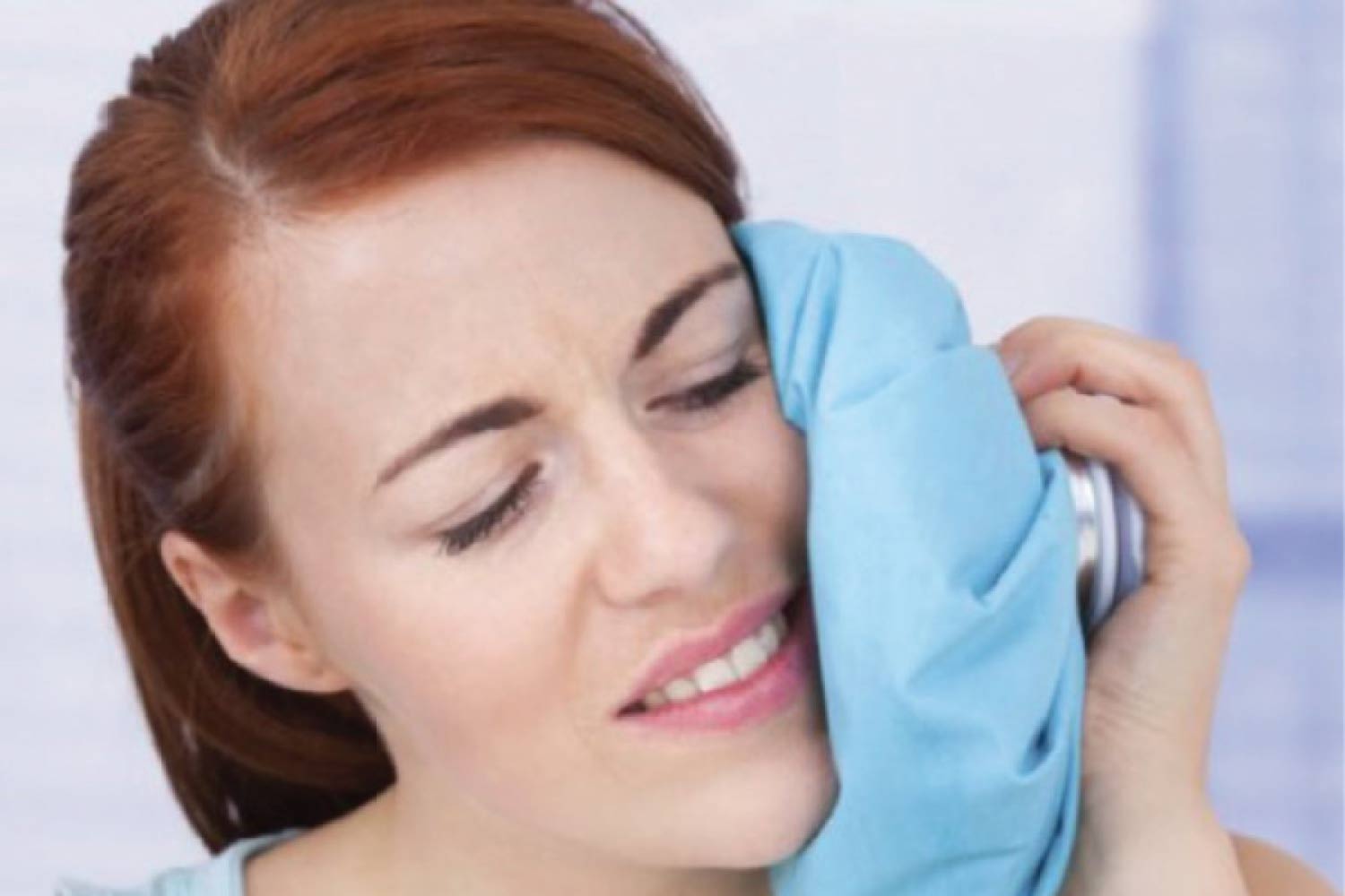 woman holds an ice pack to her jaw to relieve a tooth abscess