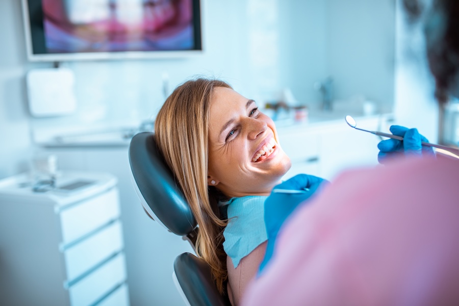 smiling woman in dental chair considering all-on-4 dentures, implant supported dentures